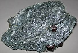 This is a piece of mica schist. There are two garnets embedded inside, a common occurence.